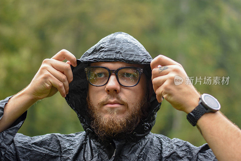 一个小男孩在一场大雨后修他的斗篷