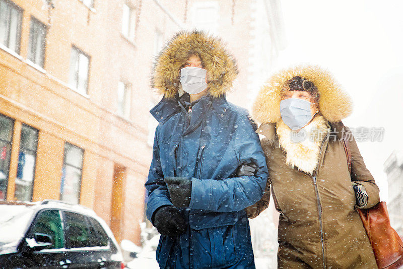 母亲和儿子走在城市设置在一个下雪的冬天戴着面具