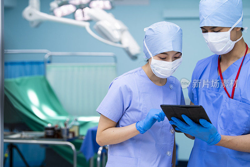 女医生和外科医生在手术室检查数字病人图表