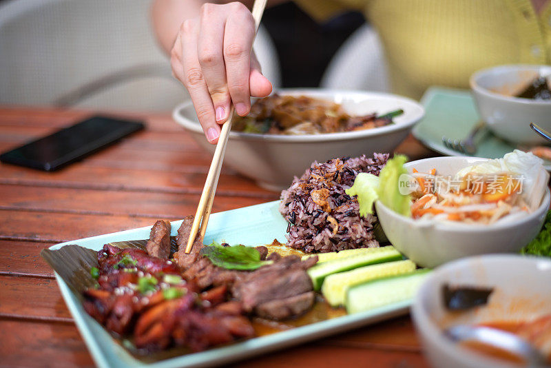 一个女人正在吃泰国烤肉鸭和牛肉