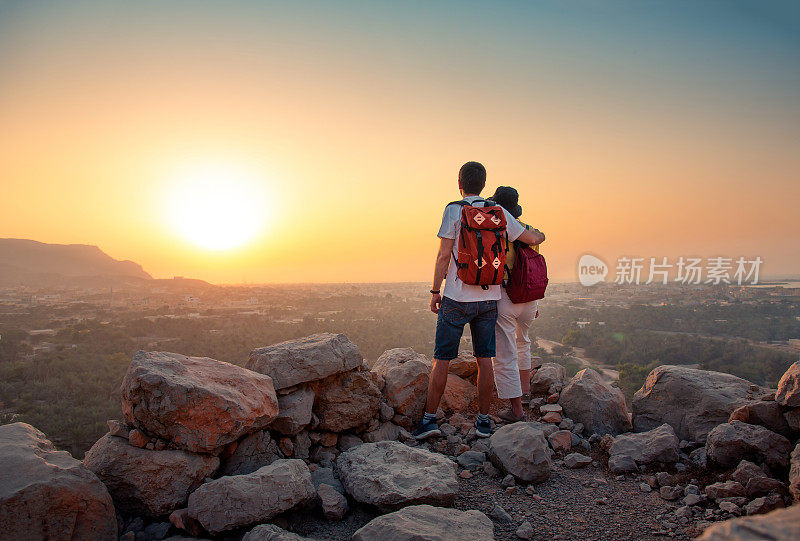 一对夫妇在阿联酋沙漠的山顶上欣赏日落的景色