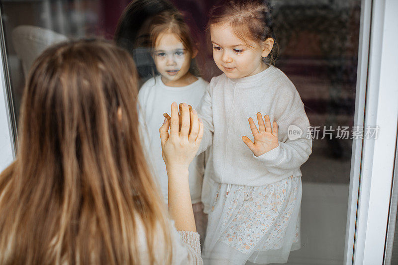 一个女儿通过窗户探望被隔离的母亲，防止她感染冠状病毒