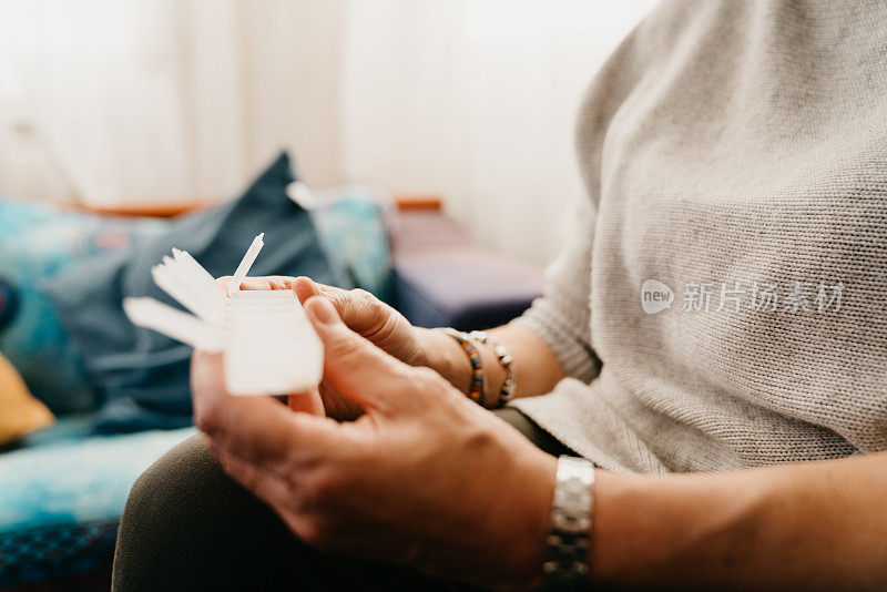 特写拍摄了一位正在服用和整理药物的成熟女性