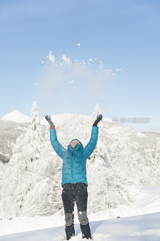 在冬天的森林里，成熟的女人穿着皮大衣向空中抛雪