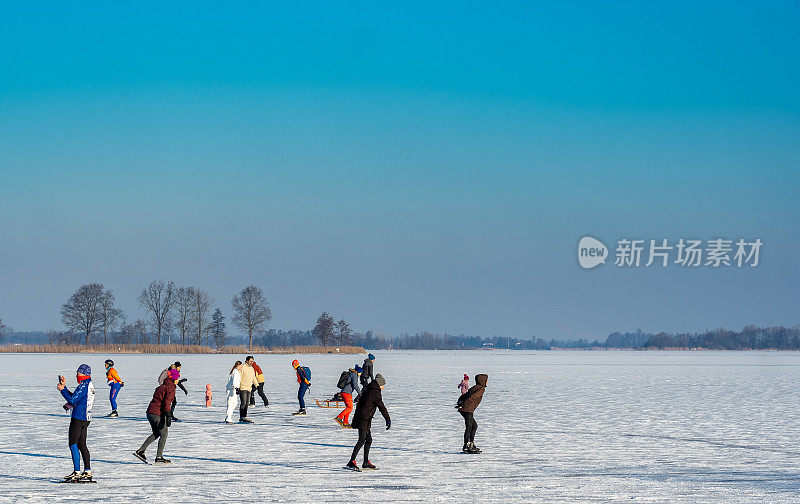 在阳光灿烂的天空下，爱运动的人们在天然的冰上溜冰