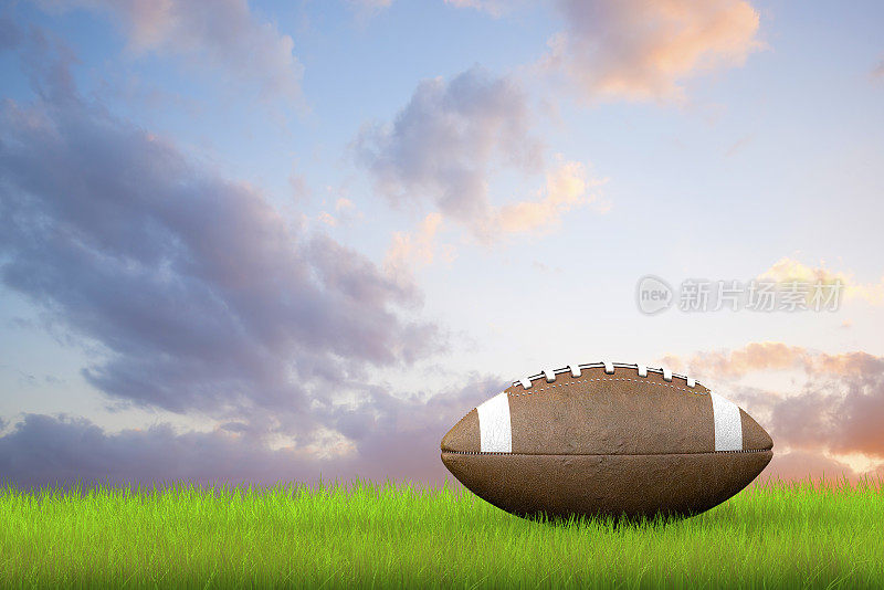 美式足球在绿色的田野和多云的天空后面踢球