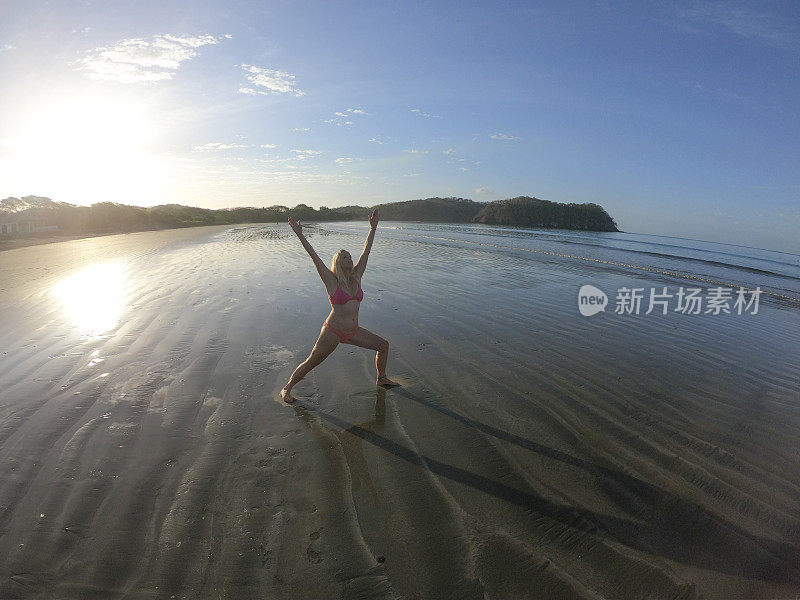 早上，一名女子在沙滩上做瑜伽动作