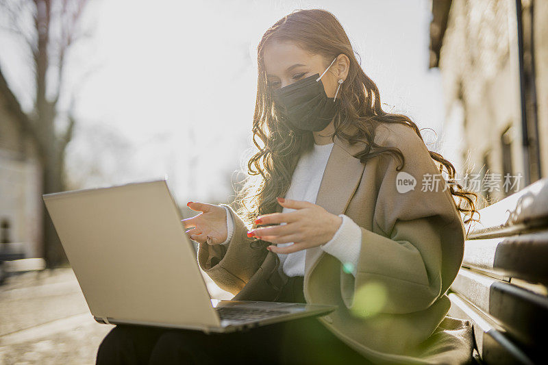 在冠状病毒大流行期间使用笔记本电脑并在户外工作的女商人