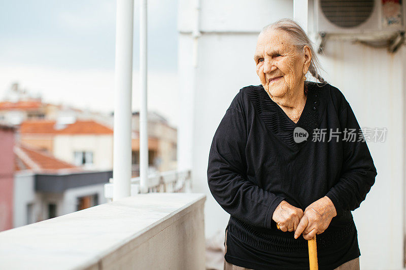 阳台上拄着拐杖的老妇人