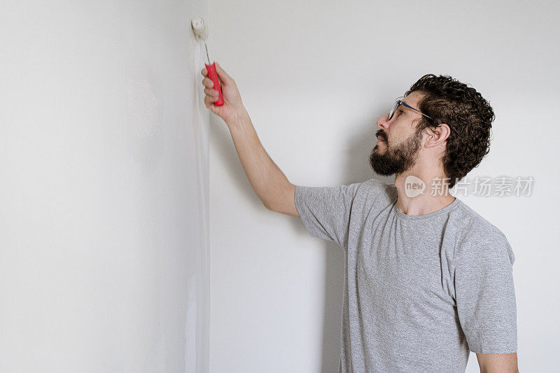 一个男人正在粉刷新公寓的墙壁，准备搬进去