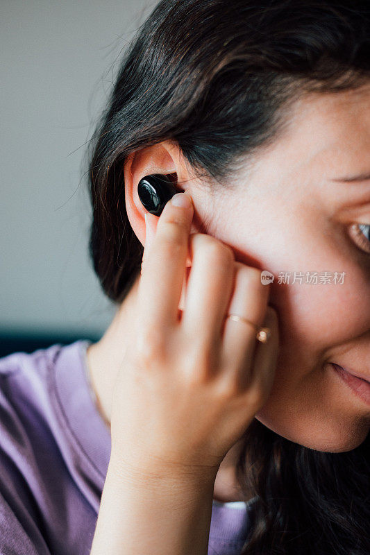 女人戴着无线耳机，拿着智能手机