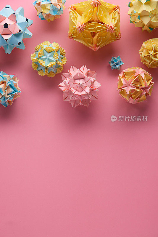 Set的multicolorÂ手工制作modularÂ折纸球或Kusudama孤立在粉红色的背景。视觉艺术，几何学，折纸艺术，纸工艺品。俯视图，特写，选择性聚焦，复制空间。