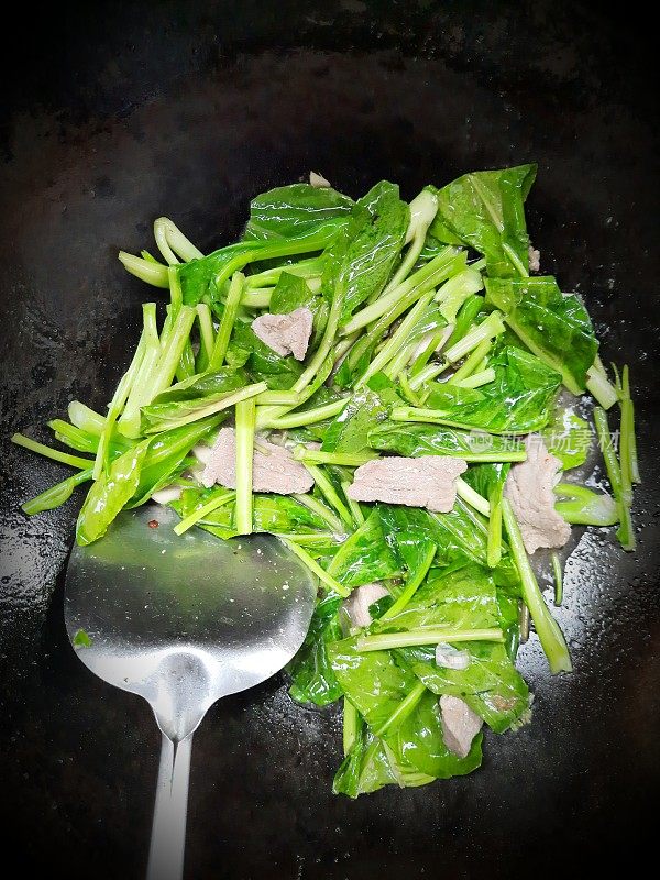 在铁锅里用猪肉炒甘蓝菜。