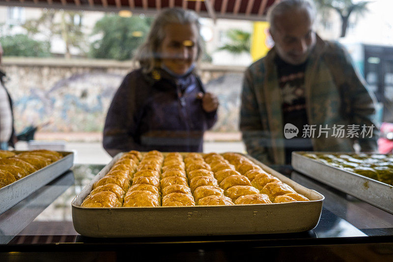 老夫妇在果仁饼店的橱窗里挑选果仁饼