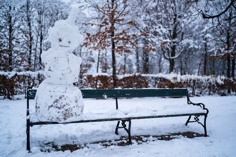 冬天，一个有趣的雪人坐在公园的长椅上