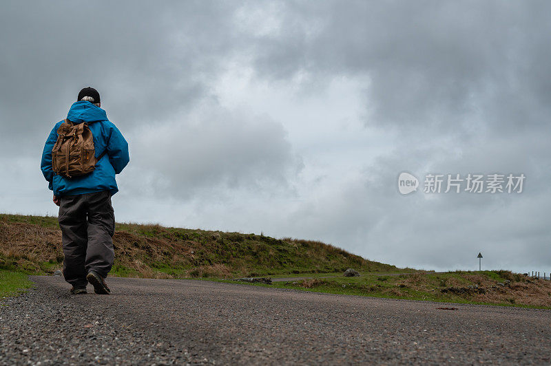 一位活跃的老人在偏远的乡村道路上徒步旅行