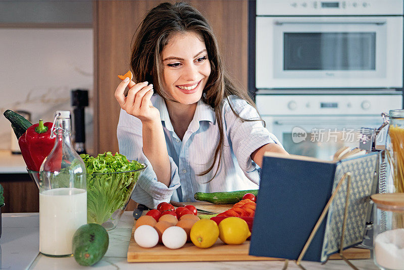 一个年轻女人在厨房里看烹饪书的肖像