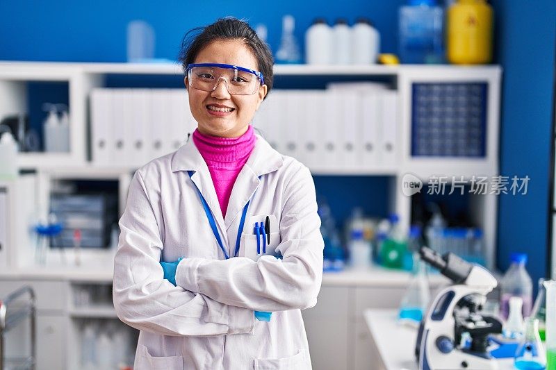 年轻的中国女科学家微笑着自信地站在实验室，双手交叉