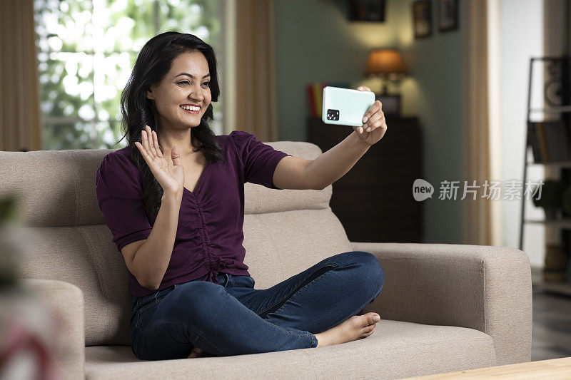 年轻女子在家里用手机视频通话股票照片