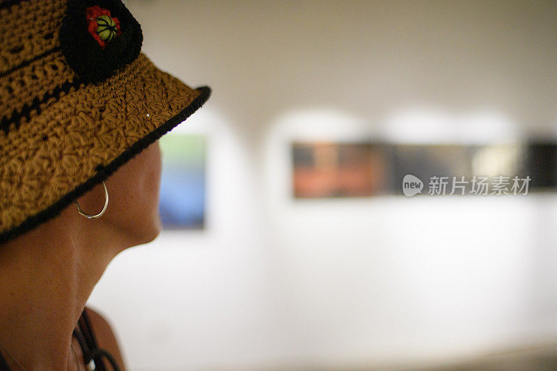 一个戴帽子的女人在看展览