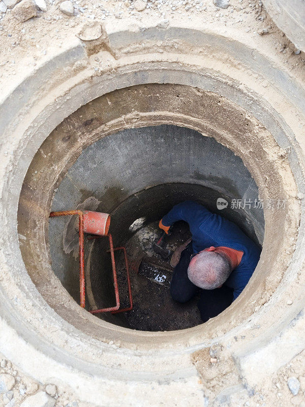 一个正在工作的水管工打开下水道的舱口。维护化粪池和水井。有选择性的重点