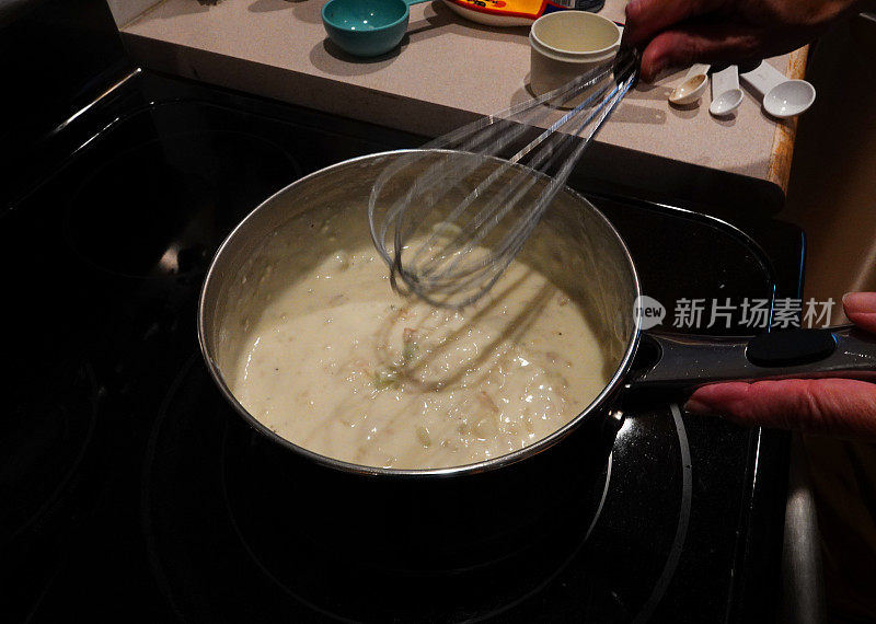 用打蛋器搅拌一锅蛤蜊浓汤。