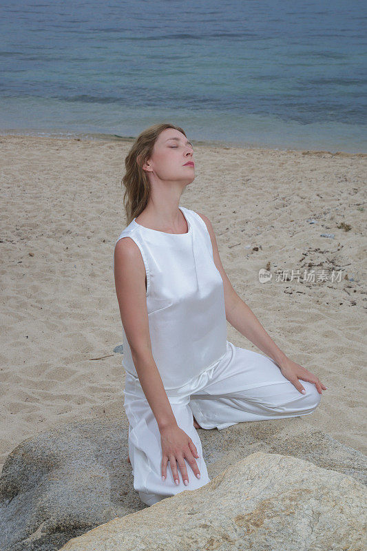 时尚户外肖像的女模特在白色丝绸服装在海滩上