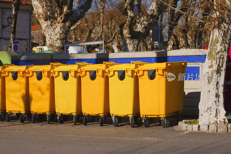 人行道边有一排黄色垃圾桶供回收。