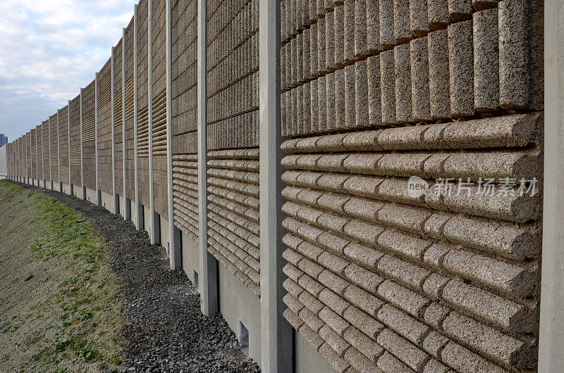 由混凝土多孔肋材料制成的隔音墙。灰色的栅栏嵌在金属横梁上，在街道上。道路交通噪音花园及住宅区。保护耶路撒冷，火箭