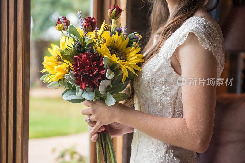 浅聚焦镜头的新娘拿着一个美丽的花束向日葵