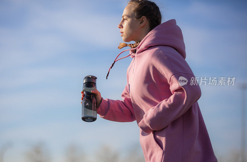 年轻女子在公园慢跑时补水。