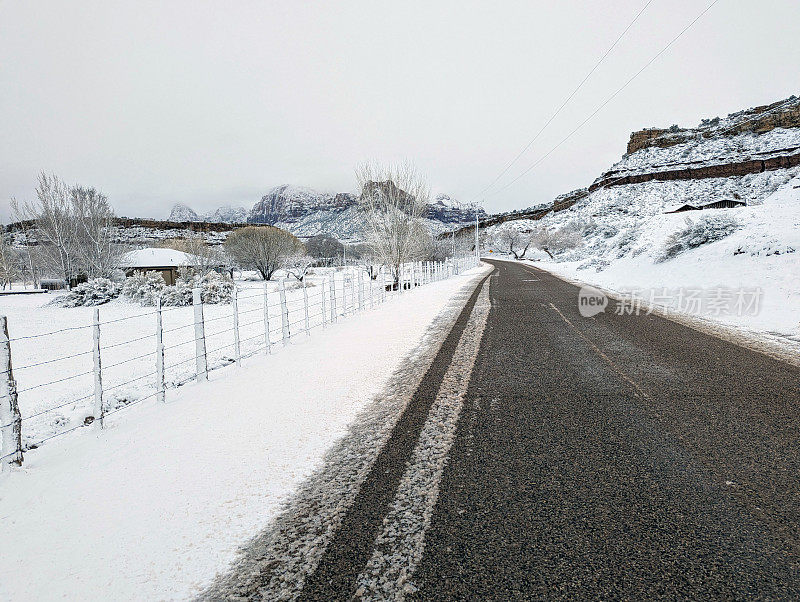 在犹他州洛克维尔，一场大雪过后，格拉夫顿路上的牧场房屋和灌溉沟渠，背景是锡安国家公园