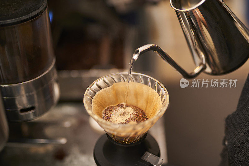 年轻的亚洲咖啡师正在煮现磨咖啡。
