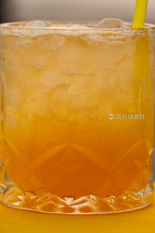 海滩餐厅酒吧场景的全帧图像，饮酒杯的龙舌兰日出鸡尾酒饮料与冰和柠檬片在布覆盖的桌子上，重点在前景