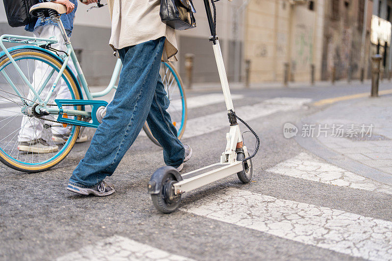 不认识的男女骑着自行车和电动滑板车在城市里穿梭