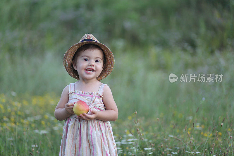 可爱的小女孩在户外吃苹果的照片