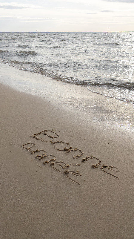 在法语中，新年快乐的文字标志意味着在沙滩上用日出和即将到来的海浪在光滑的沙滩上手写的新年祝福