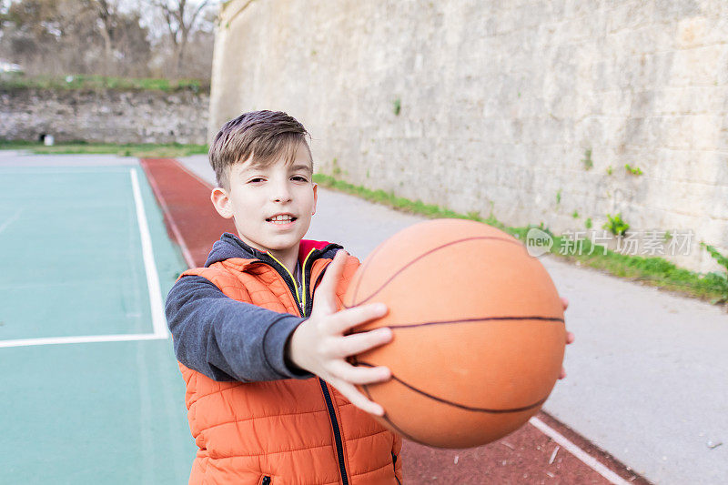 一个男孩在体育场上拿着篮球的照片。