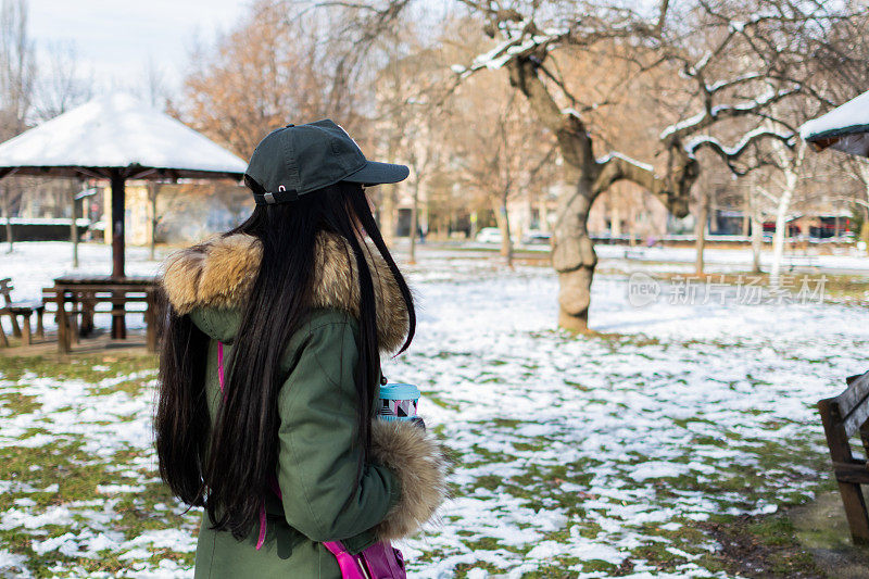 在一个下雪的冬日，一位美丽的年轻女子在公园里享受着她的咖啡。