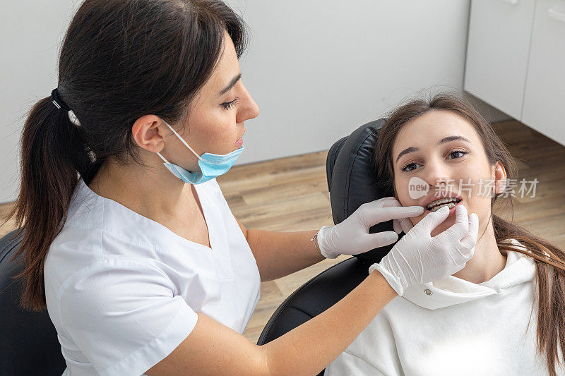 正畸医生检查女性牙齿的托槽。口腔科、牙科、牙套正畸治疗的概念