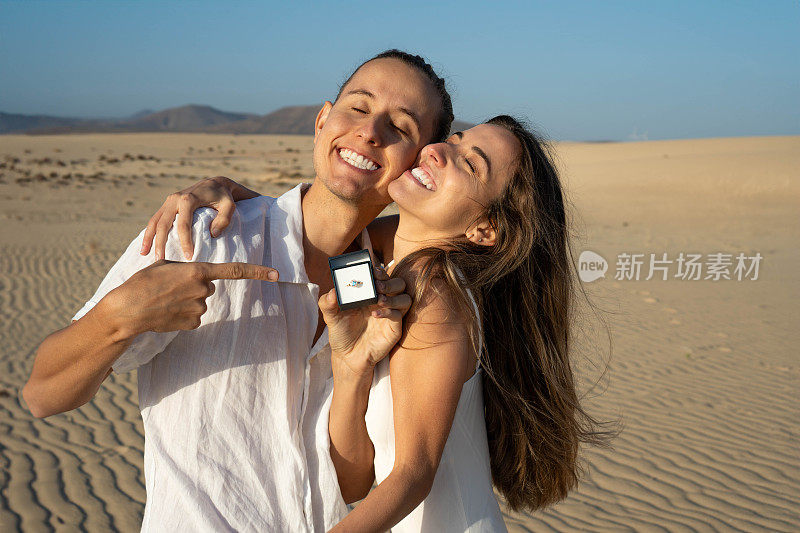 沙漠沙滩上一对戴着订婚戒指的快乐情侣