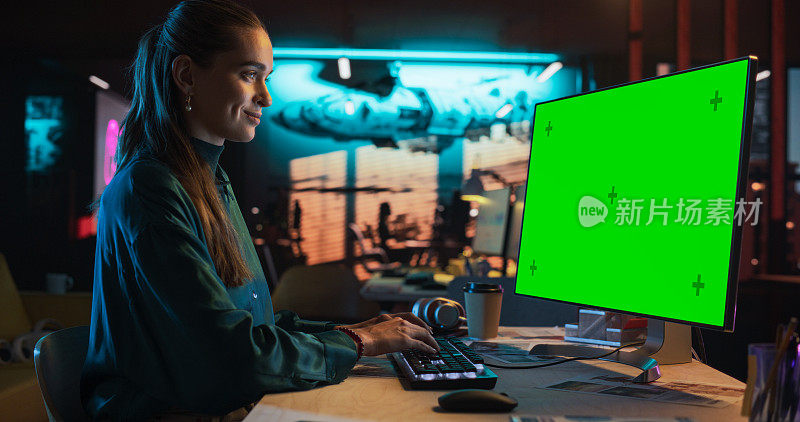 年轻女子的肖像坐在她的办公桌上使用桌面电脑与模拟绿屏。女性高加索专家工作与彩色键显示在创意机构的电脑