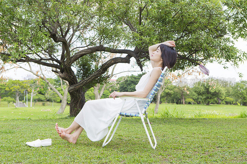年轻女人坐在躺椅上做日光浴