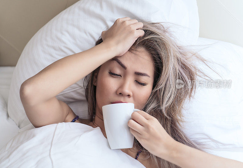 一个亚洲女人的肖像，感觉不舒服，头痛，喝茶-感冒和流感