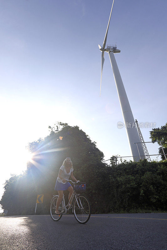 女人骑着自行车经过风力涡轮机