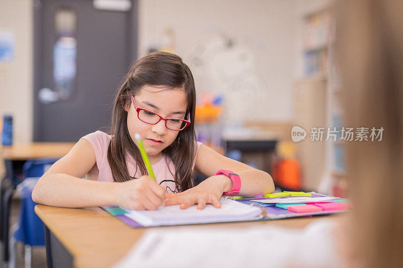 一个四年级的女孩在她的课桌上做作业