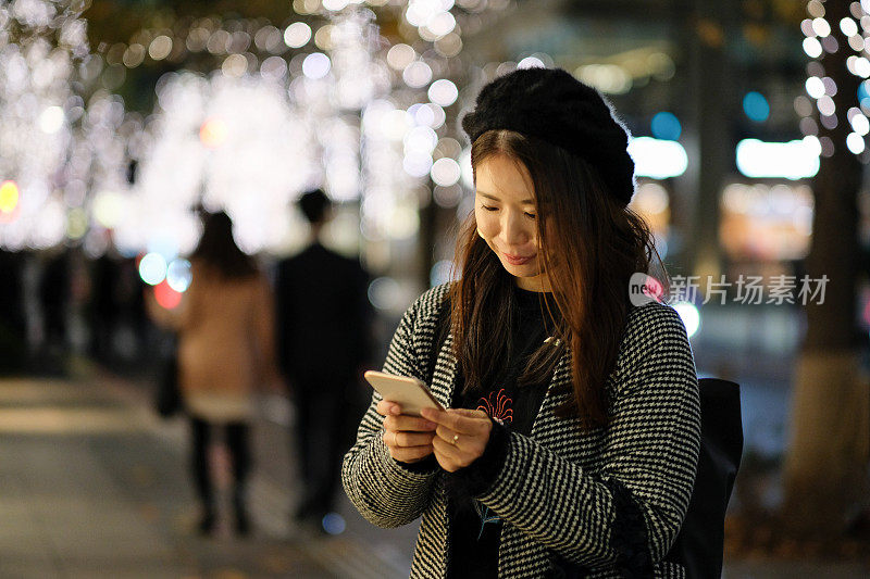 女人看智能手机在街上的照明