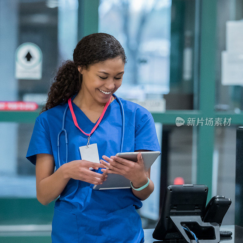 年轻的护士在医院护士站用平板电脑检查病人的病历。
