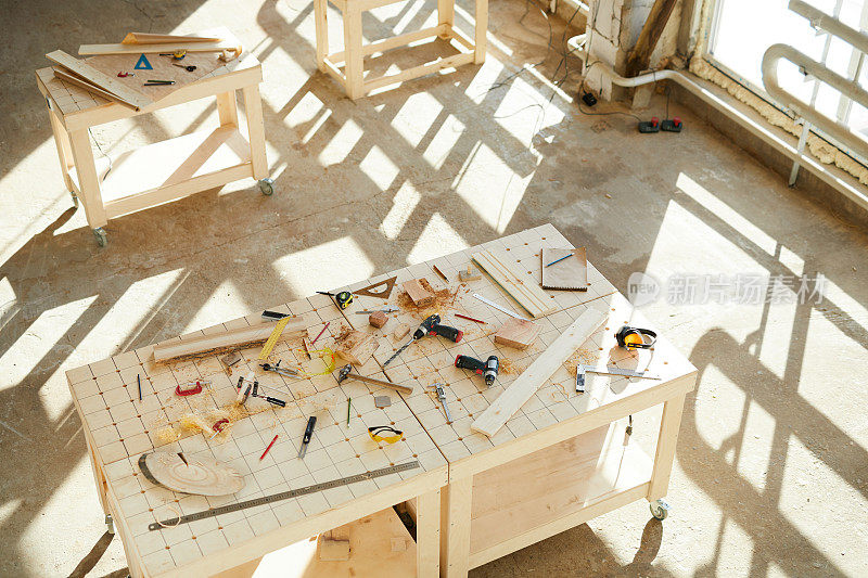 木工车间无人:四张桌子的正上方是木工的团队工作，桌上有手工工具和测量仪器