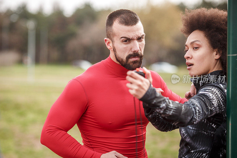 女私人教练用秒表显示她的男客户的表现和时间